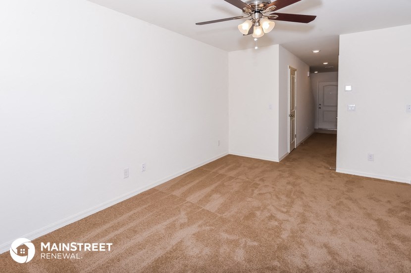 the spacious living room with carpeting and a ceiling fan