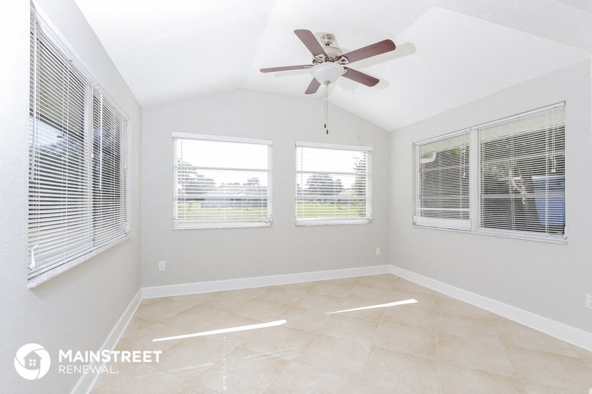 an empty room with three windows and a ceiling fan