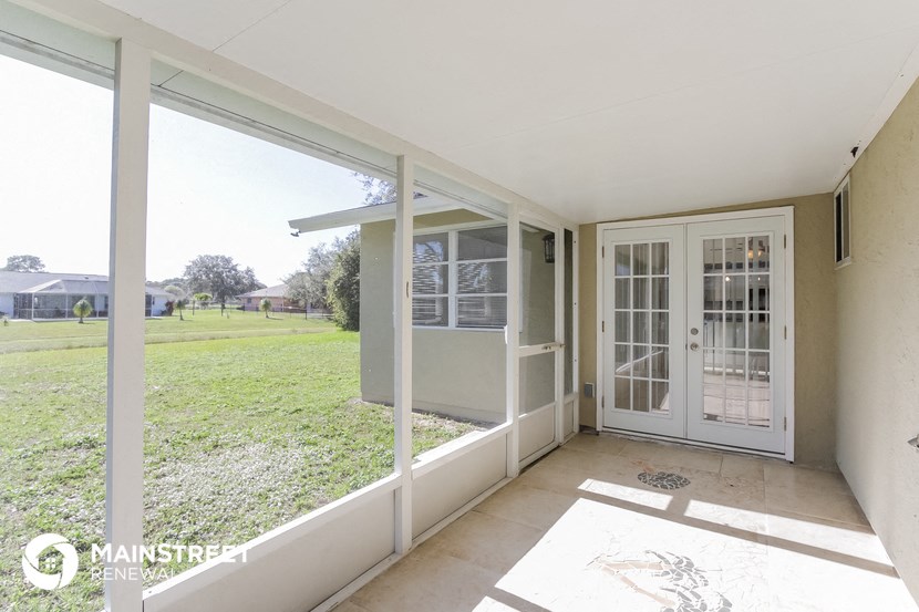 a view of the yard from the living room of a house with a patio door