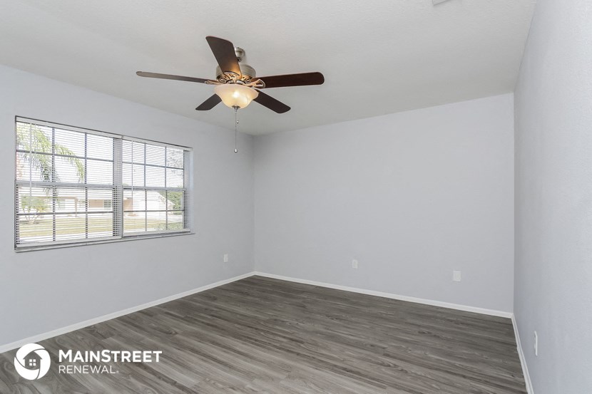 the spacious living room with a ceiling fan and a window