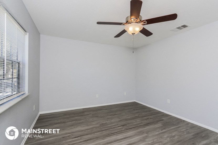 the spacious living room with ceiling fan and wood flooring