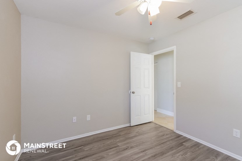 the spacious living room with a ceiling fan and wood flooring