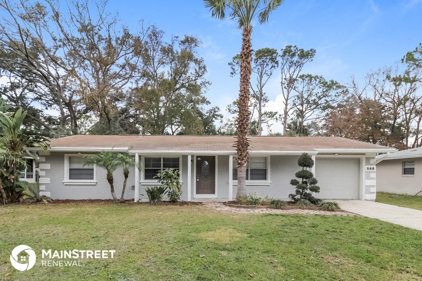 a white house with a yard and palm trees