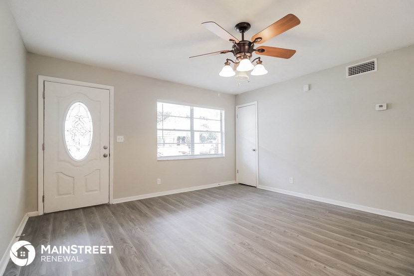 the living room of an empty house with a ceiling fan