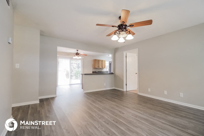 the living room and kitchen of an empty house with a ceiling fan