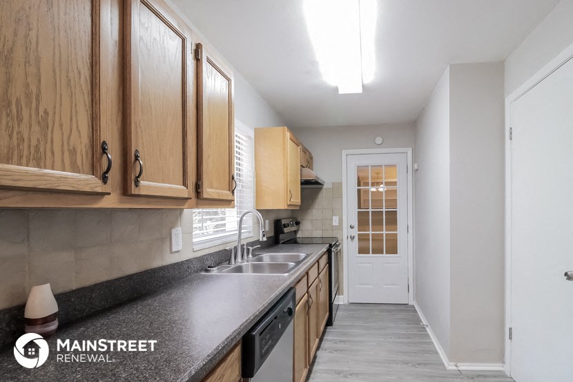 a kitchen with a sink and wooden cabinets and a white door