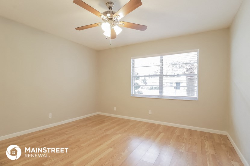 the spacious living room with wood floors and a ceiling fan