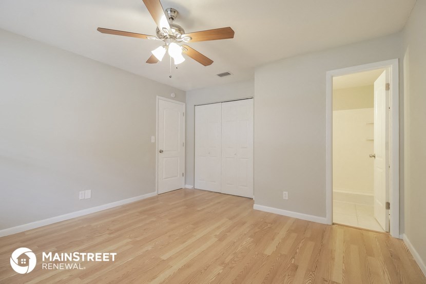 the living room of an apartment with wood flooring and a ceiling fan