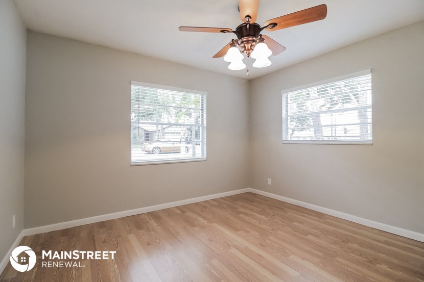 an empty room with a ceiling fan and two windows