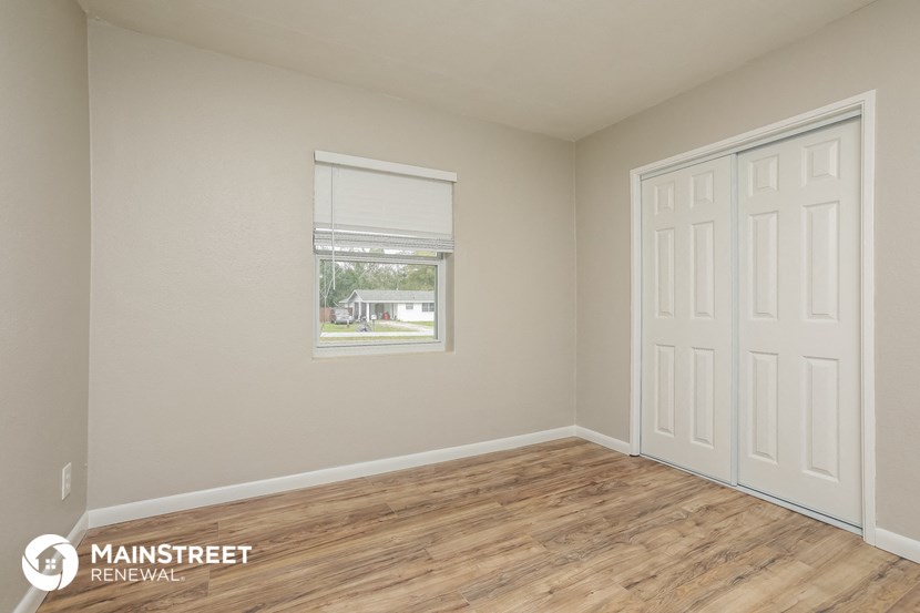 the spacious living room with wood flooring and a window