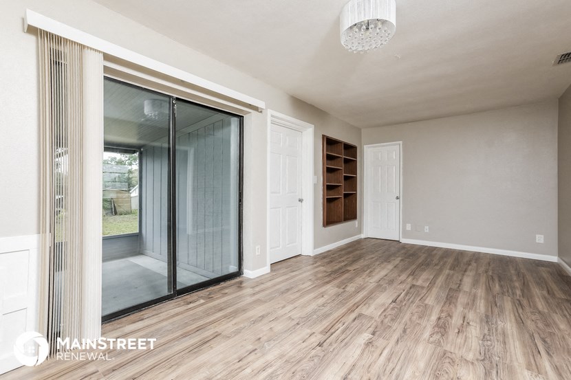 an empty living room with a sliding glass door to a walk in closet