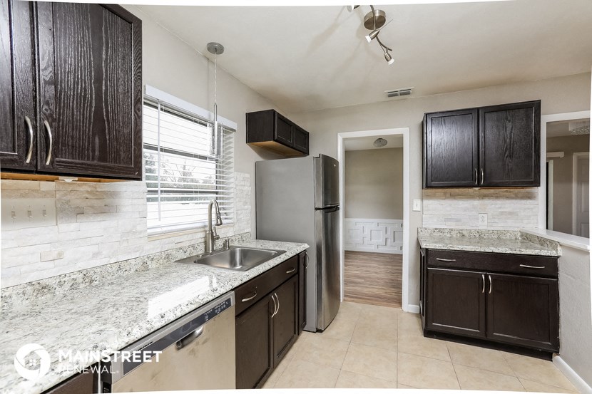 a kitchen with black cabinets and a sink and a refrigerator