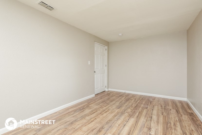 the spacious living room with wood flooring and white walls