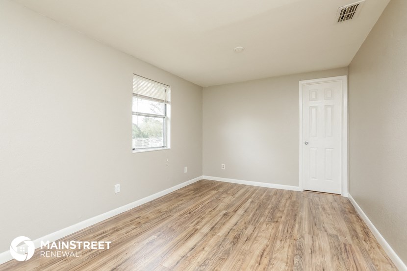 the spacious living room with wood flooring and a white door
