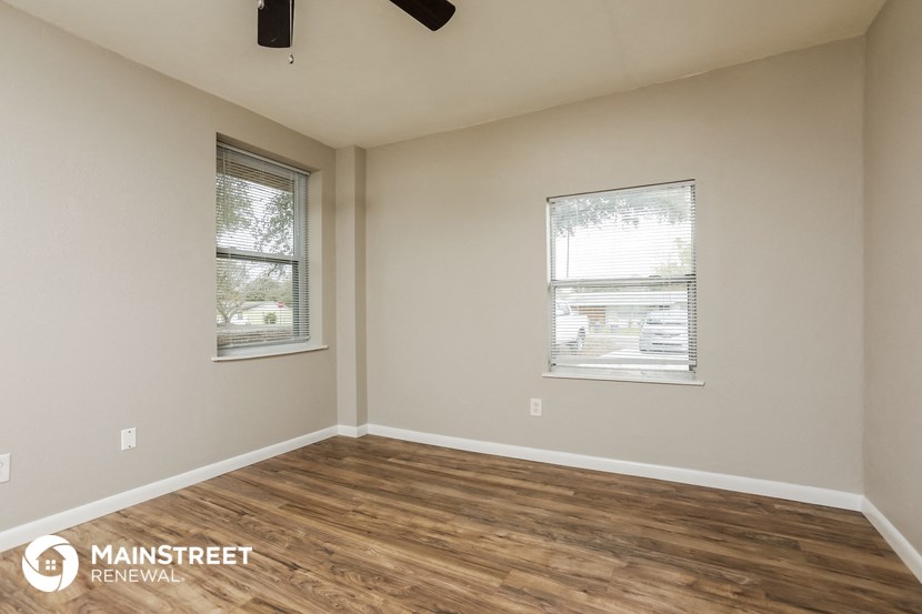 the interior of an empty room with wood flooring and two windows