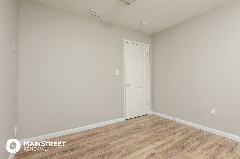 the upstairs bedroom with wood flooring and a white door