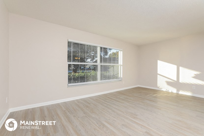 the spacious living room with a large window and wood flooring