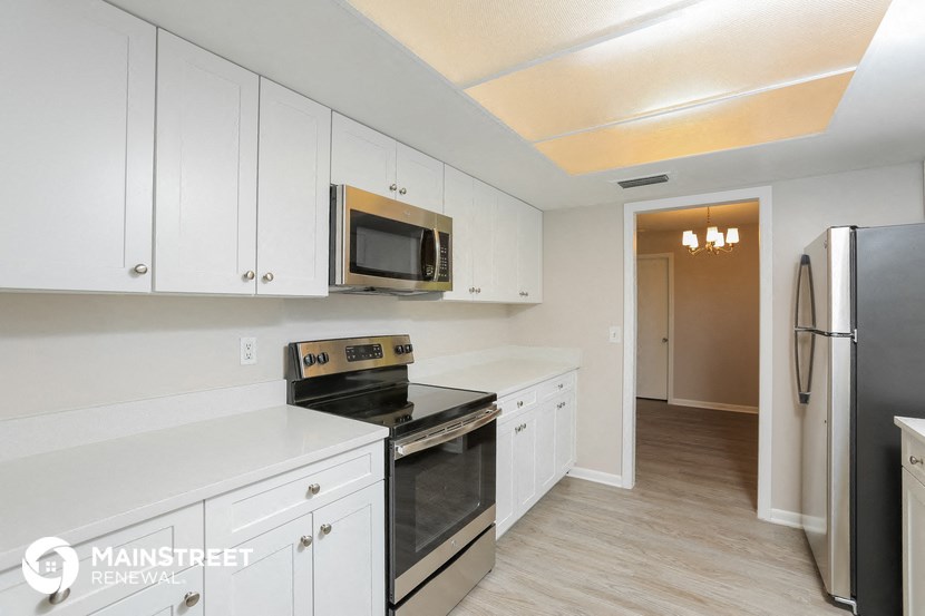a white kitchen with stainless steel appliances and white cabinets