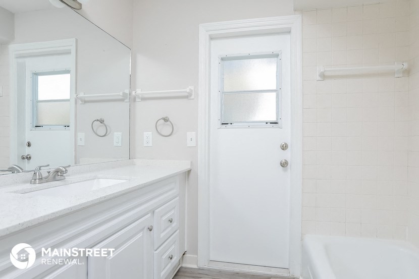 a white bathroom with a tub and a sink and a mirror