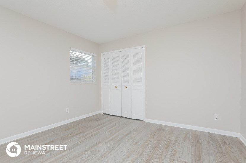 the living room of an apartment with wood floors and white walls