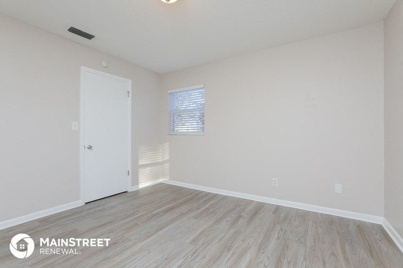 the spacious living room with wood flooring and white walls
