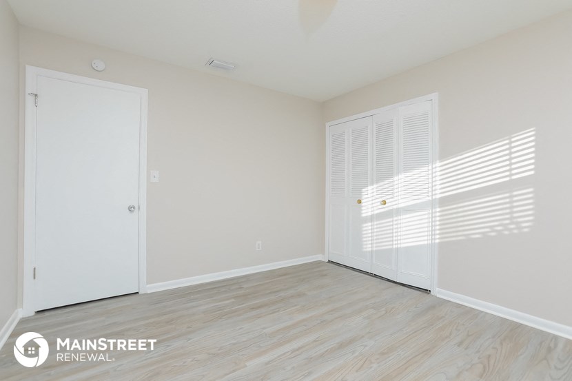 the living room of an apartment with white walls and wood flooring