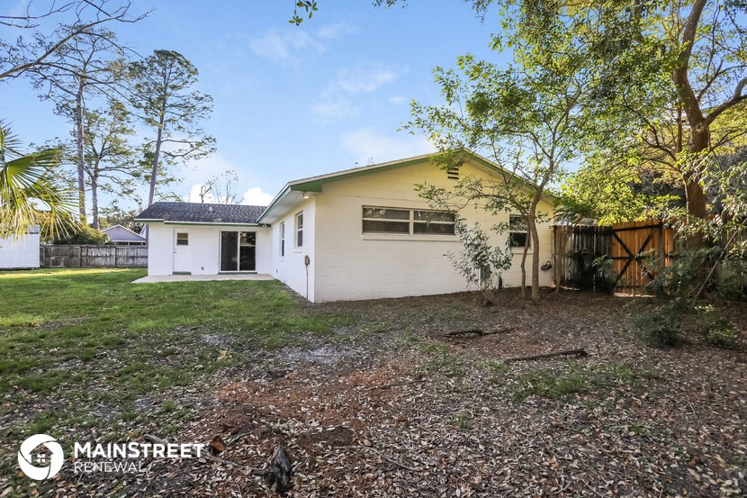a small white house with a yard and trees