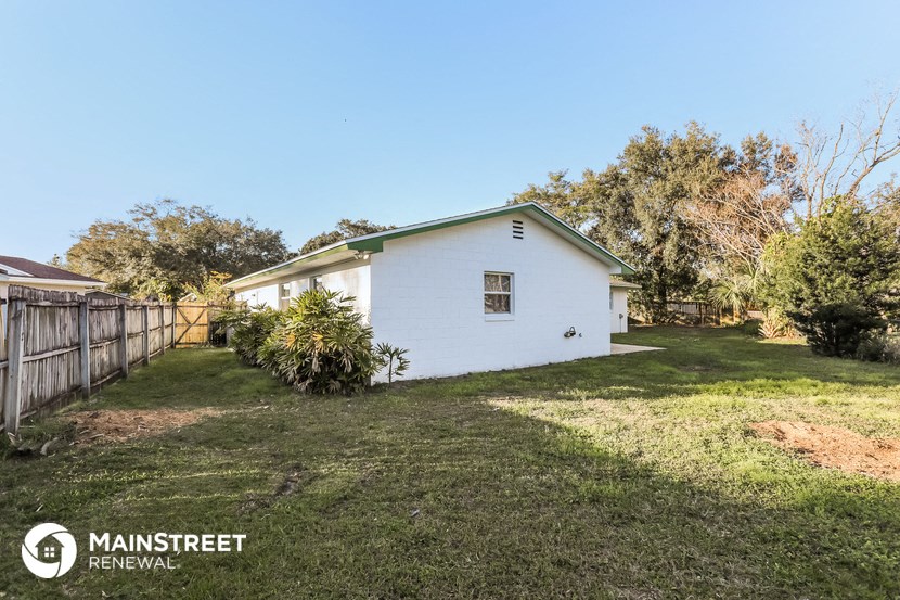 a small white house with a yard and a fence