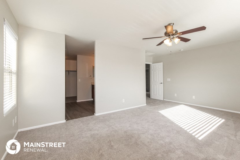 the spacious living room with ceiling fan and carpeting