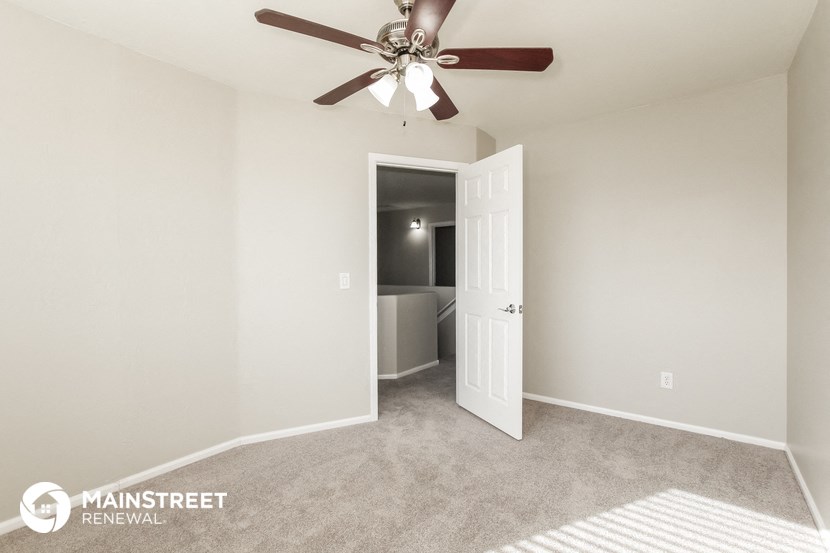 the spacious living room with ceiling fan and carpeted flooring