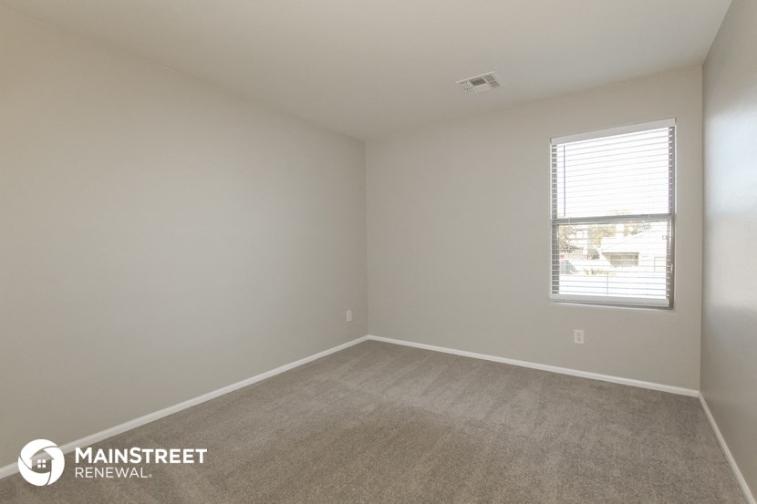 the bedroom of an apartment with carpet and a window
