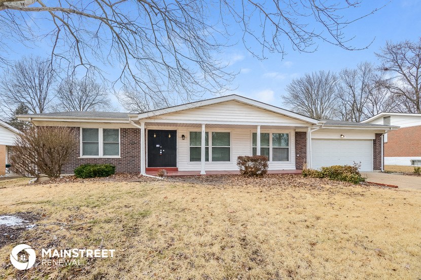 a small brick house with a yard and a black door