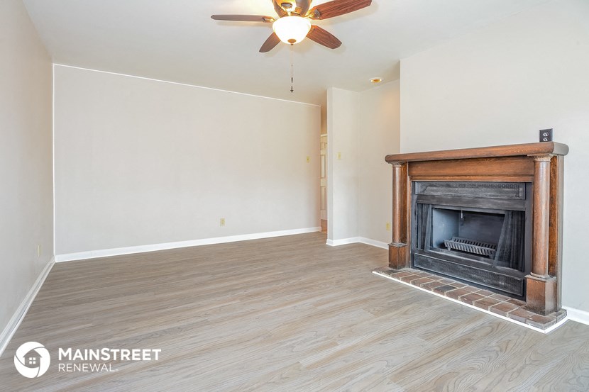 a living room with a fireplace and a ceiling fan