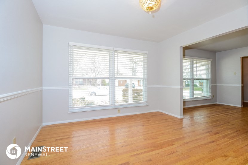 the living room of a home with wood floors and a large window