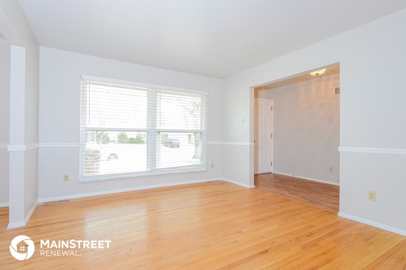 the living room of a home with wood floors and a large window