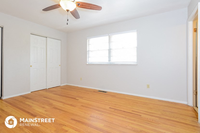 the living room with wood floors and a ceiling fan