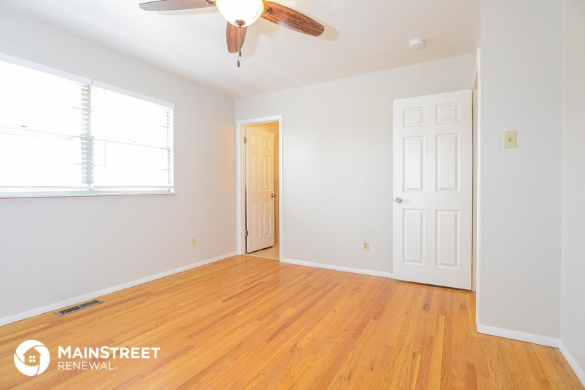 the living room of a home with wood floors and a ceiling fan