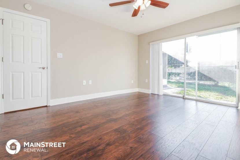 an empty living room with wood floors and a large window