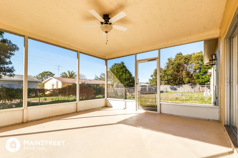 a covered porch with a ceiling fan and sliding glass doors