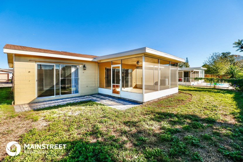 a small yellow house with a lawn and a patio
