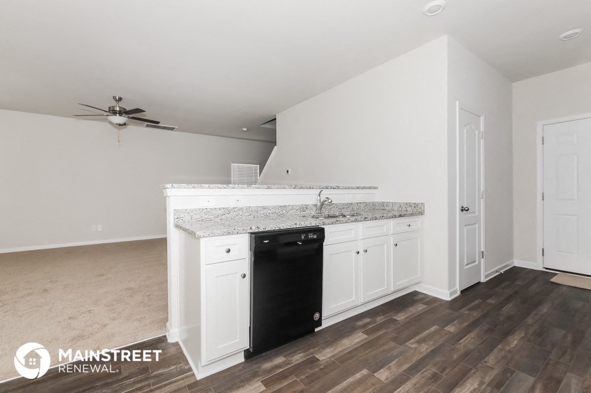 a kitchen with white cabinets and a black dishwasher and a counter top