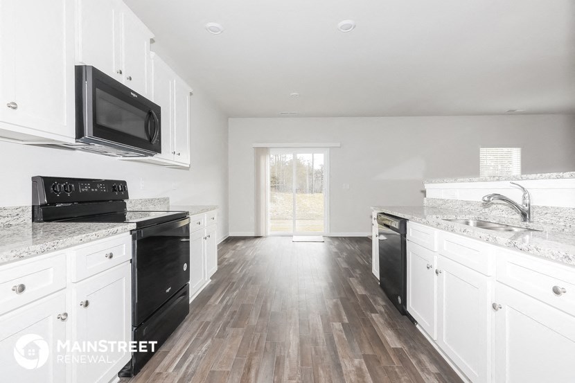 a kitchen with white cabinets and a black stove and a microwave