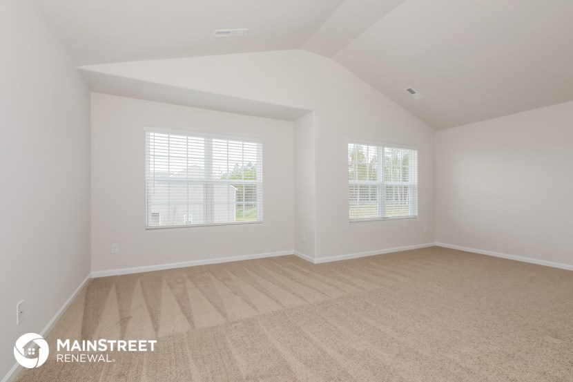 the living room of a home with white walls and wood floors