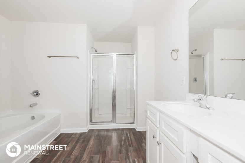 a bathroom with white cabinets and a shower and a bath tub