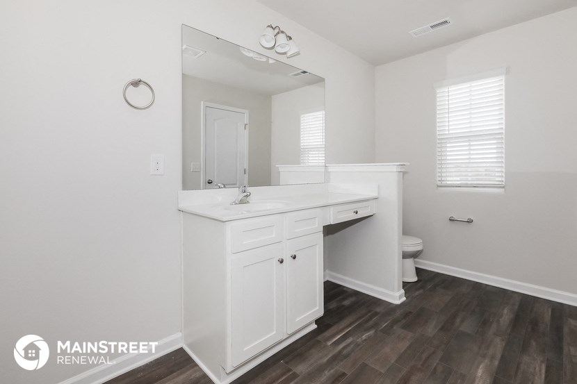 a white bathroom with a large mirror and a sink and a toilet