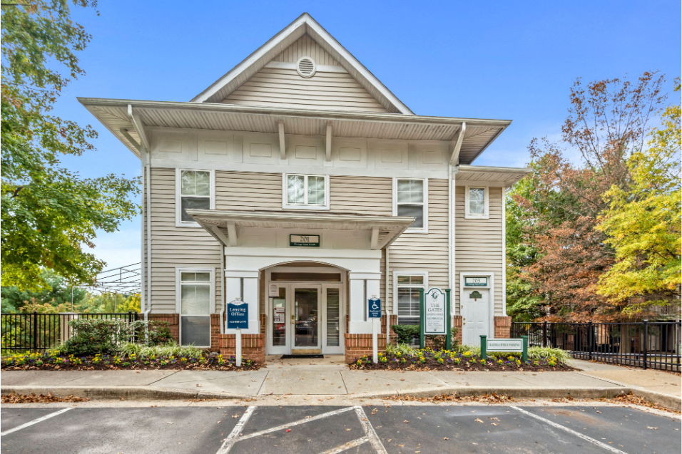 A kaki-colored building in front of blue skies with mature trees on either side