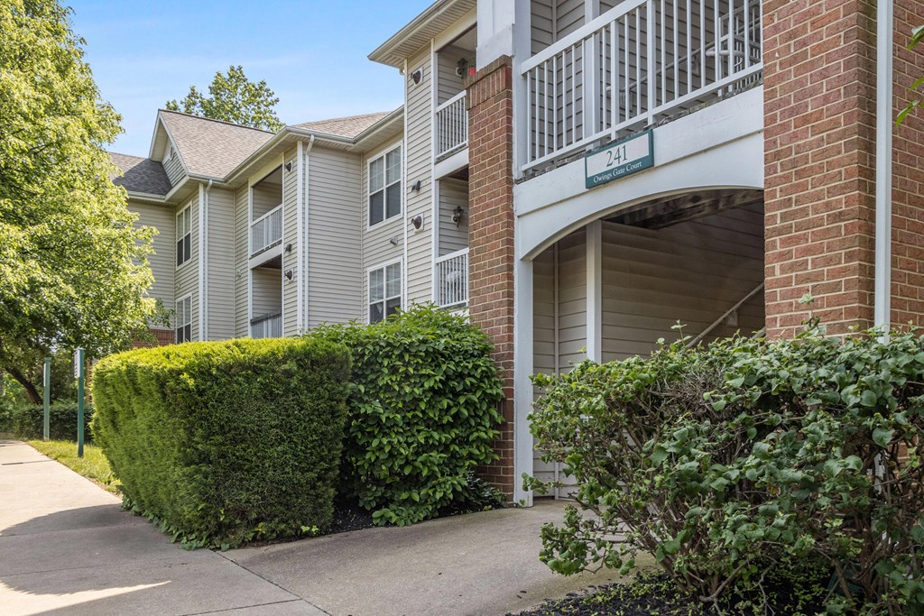 an apartment building with a sidewalk and hedges