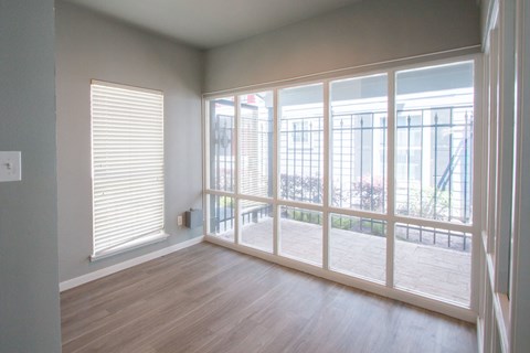 an empty living room with large windows and wood flooring