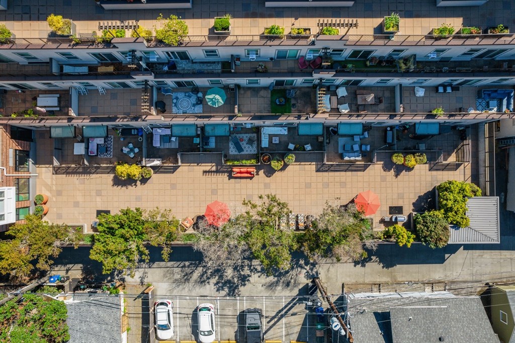 an aerial view of an urban neighbourhood with cars parked on the street and trees