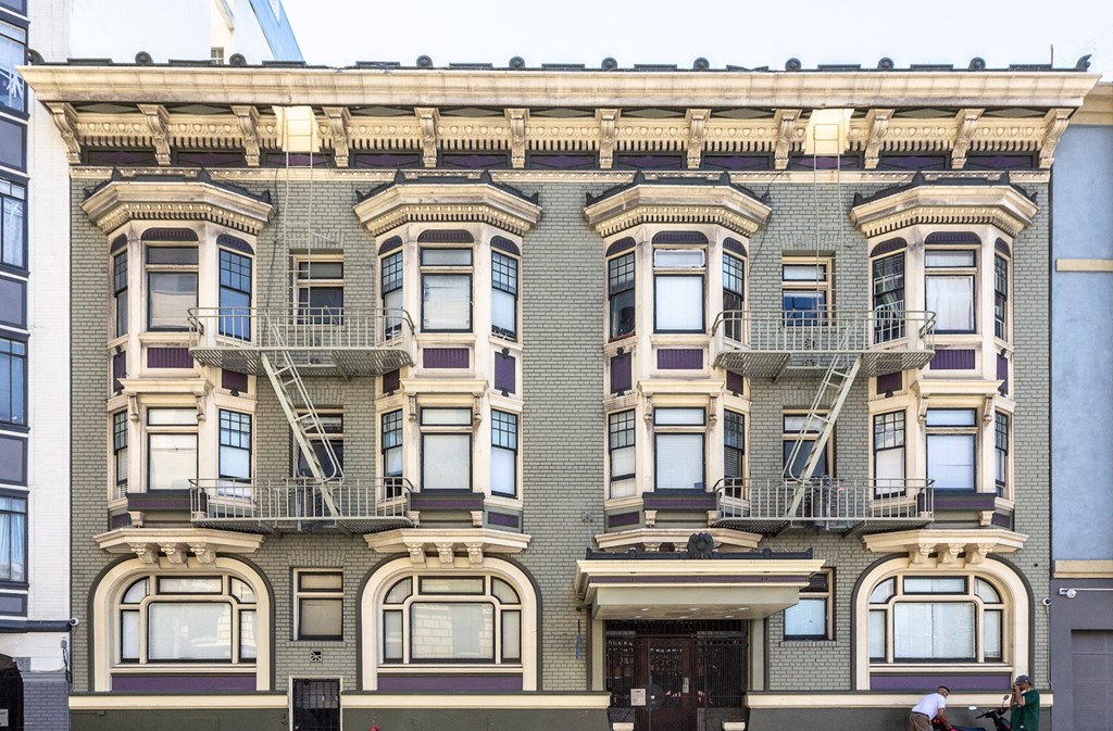 the facade of a brick apartment building with fire escapes